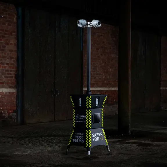 A Safer Pod S3 security unit stands in a dimly lit, industrial space against a brick wall.