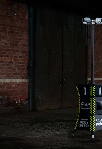 A Safer Pod S3 security unit stands in a dimly lit, industrial space against a brick wall.