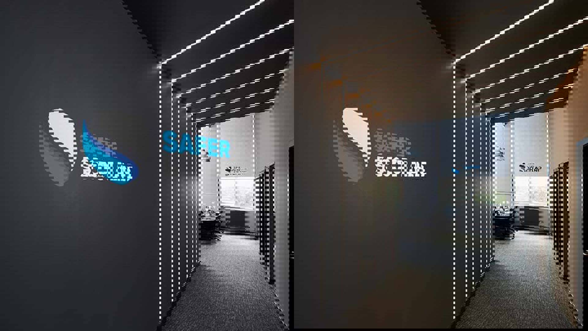 A sleek office hallway featuring a "Safer Scotland" logo on the wall, with modern lighting and glass-panelled meeting rooms.