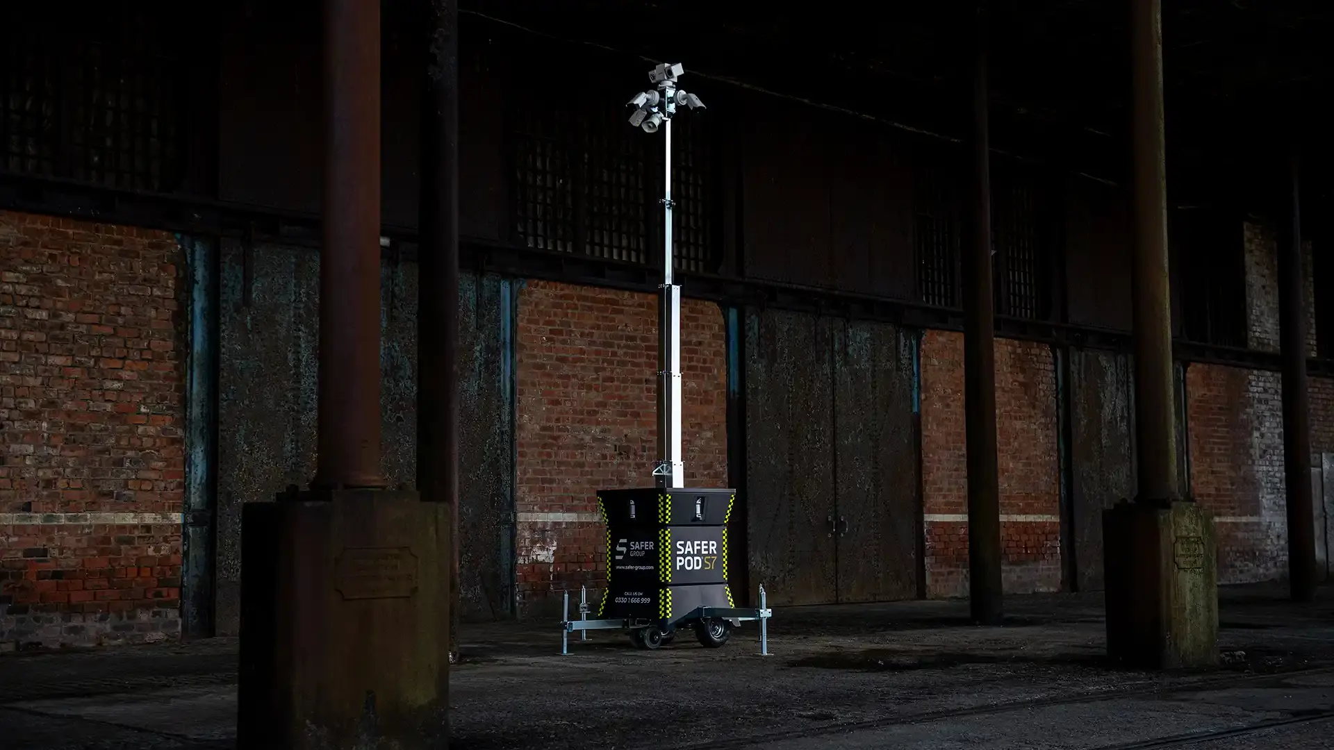 A Safer Pod S7 stands on a concrete floor beneath an industrial structure with brick walls.