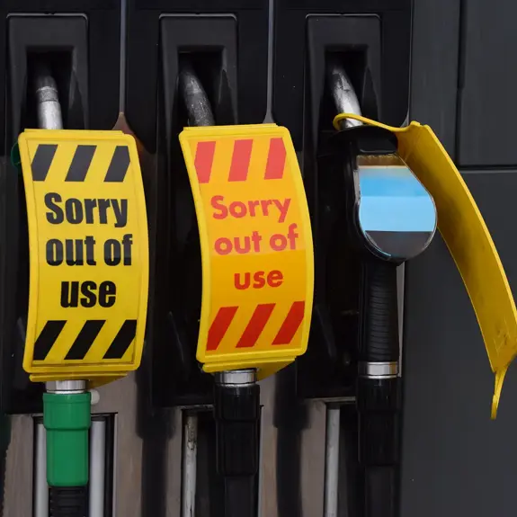 Three fuel dispensers at a petrol station, each marked with yellow "Sorry out of use" signs, indicating they are not operational.
