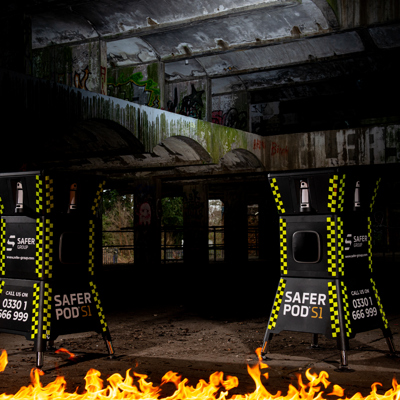 two safer pod s1 devices stand in a dark underground setting, with a strip of fire illuminating the scene. 