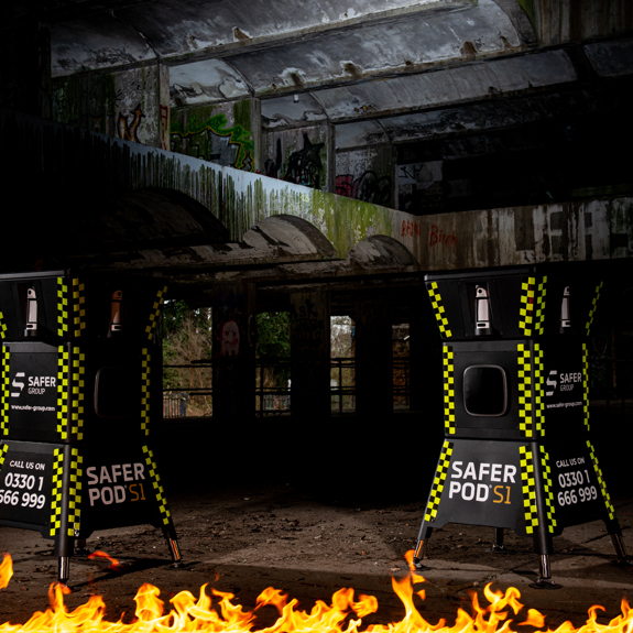 two safer pod s1 devices stand in a dark underground setting, with a strip of fire illuminating the scene. 
