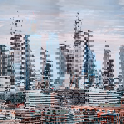 landscape of a modern busy city on a cloudy day, with old and modern architecture combined between large glass structures and older brick buildings