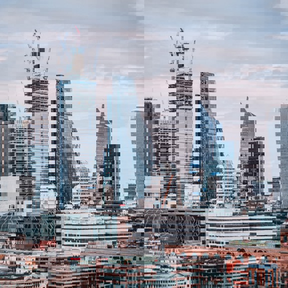 landscape of a modern busy city on a cloudy day, with old and modern architecture combined between large glass structures and older brick buildings